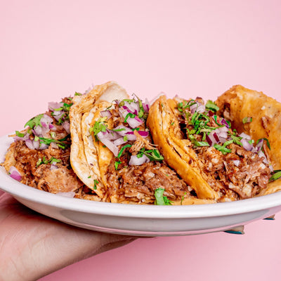 holding up a plate of homemade birria tacos