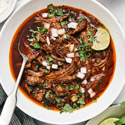 Authentic birria tacos with melted cheese and consommé, made using Spicito Birria Bombs in a slow cooker