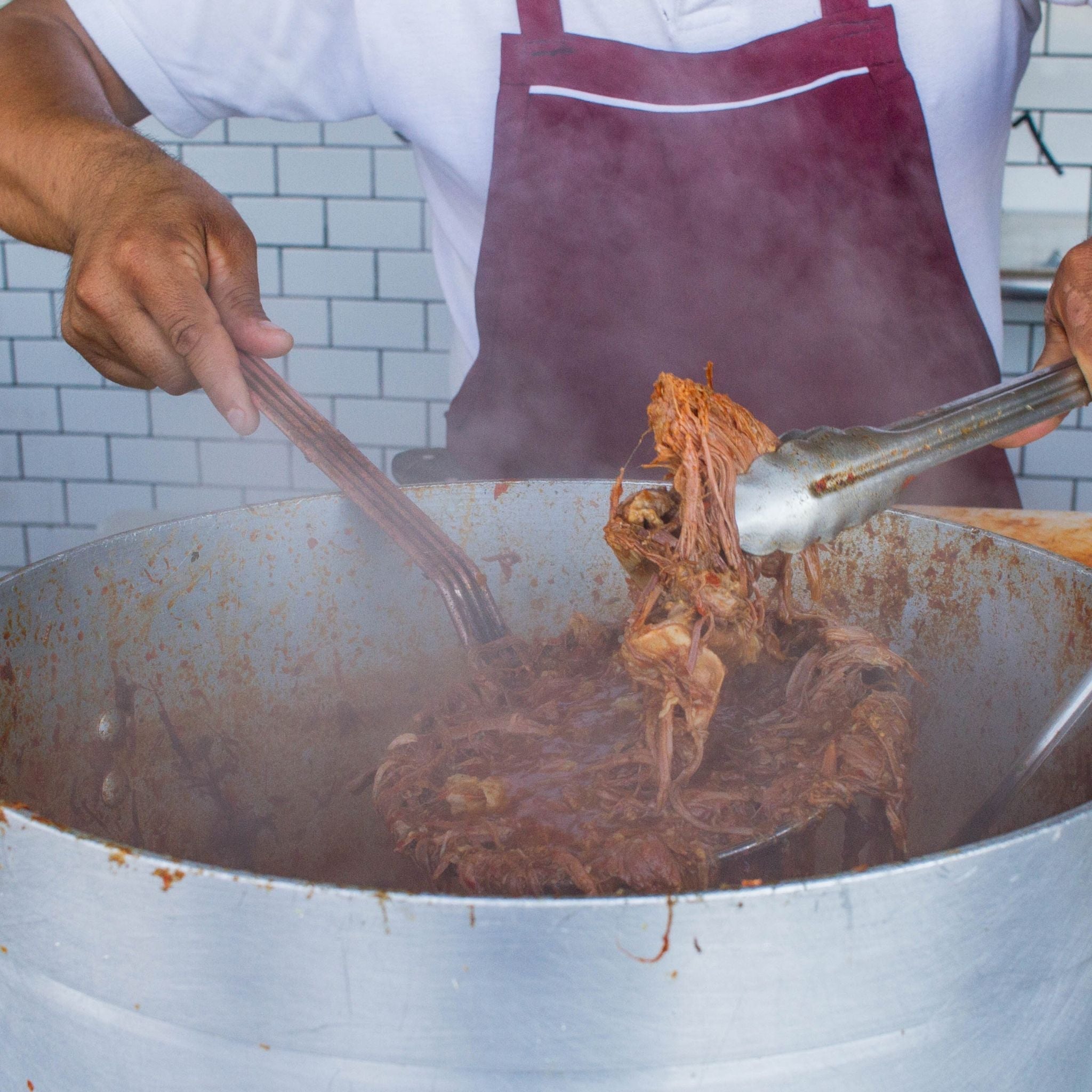 Big pot of birria simmering in consommé, perfect for feeding a crowd.