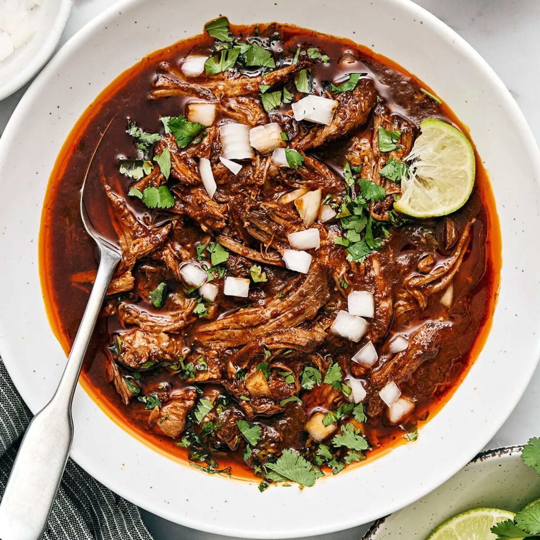 Authentic birria tacos with melted cheese and consommé, made using Spicito Birria Bombs in a slow cooker