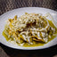 Plated dish of chilaquiles with green sauce, cheese, and onions on a white plate.