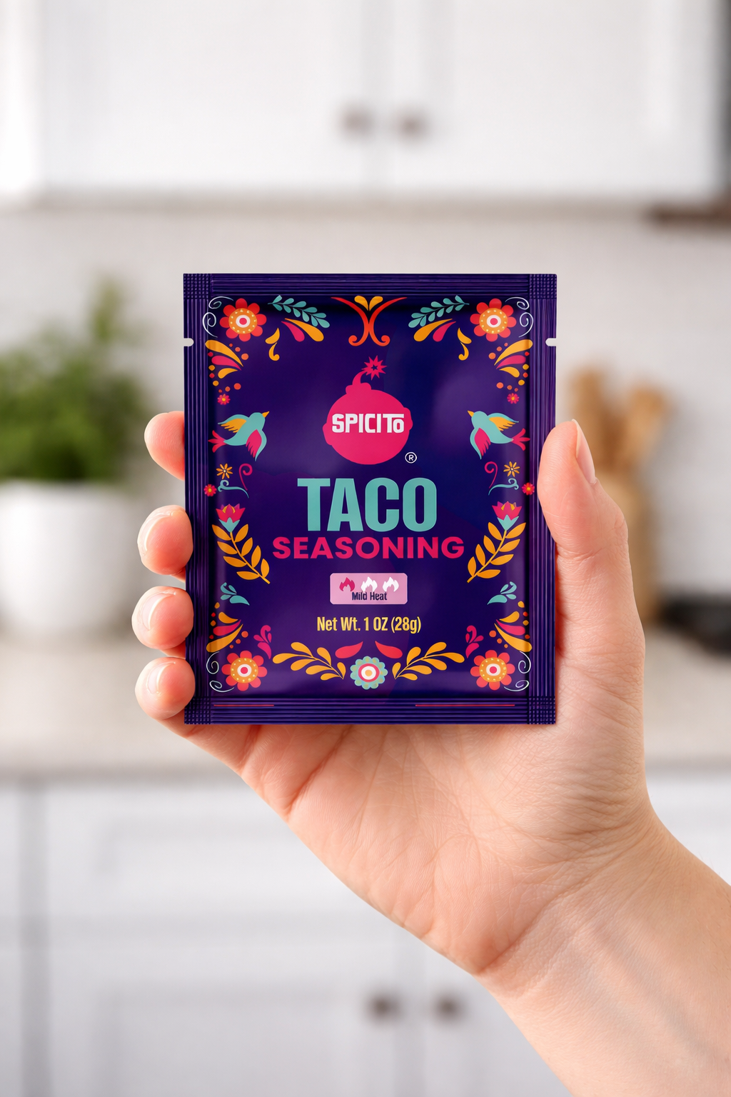 Hand holding a Spicys Taco Seasoning packet in a kitchen setting