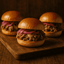 Three sliders with pulled pork and red onions on a wooden board